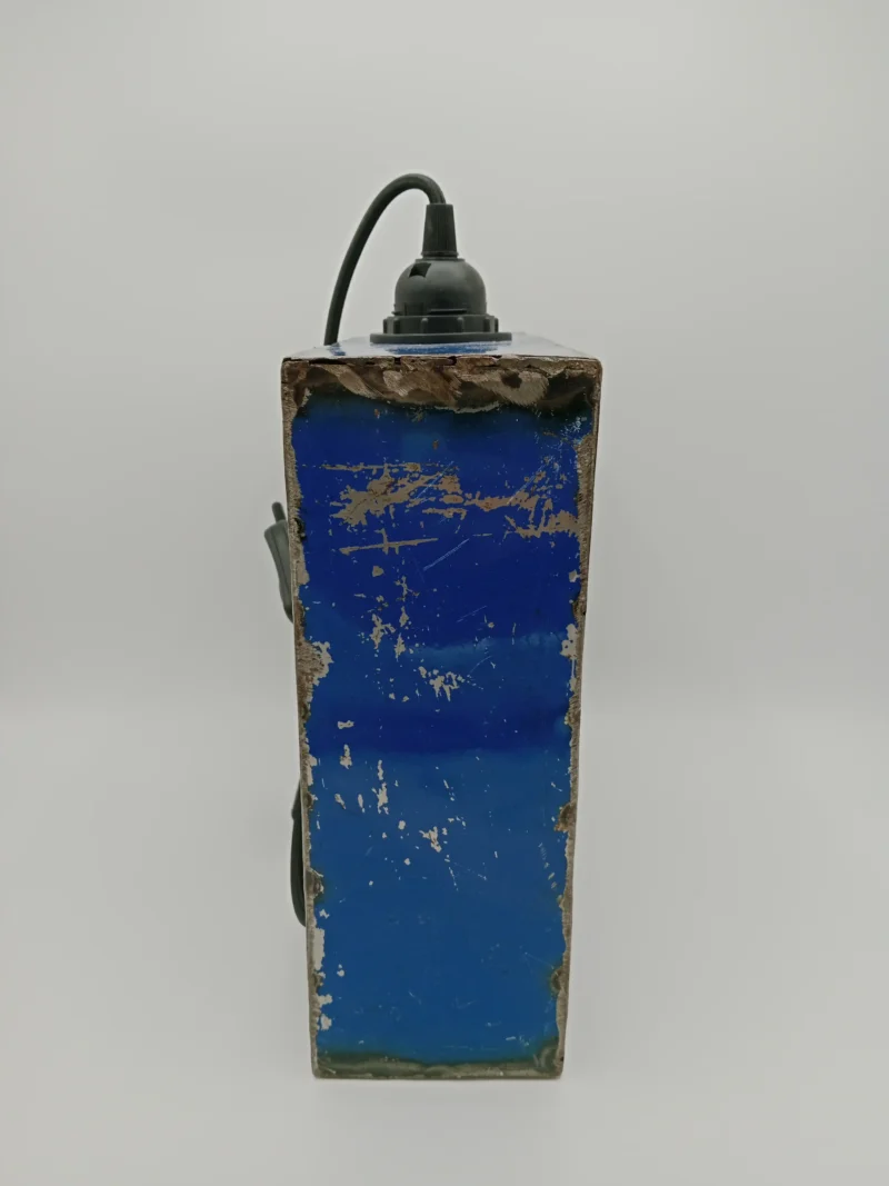 Handgefertigte Lampe aus recycelten Ölfässern mit schwarzem Textilkabel und warmweißer Vintage-Glühbirne. Nachhaltiges Design aus Burkina Faso.