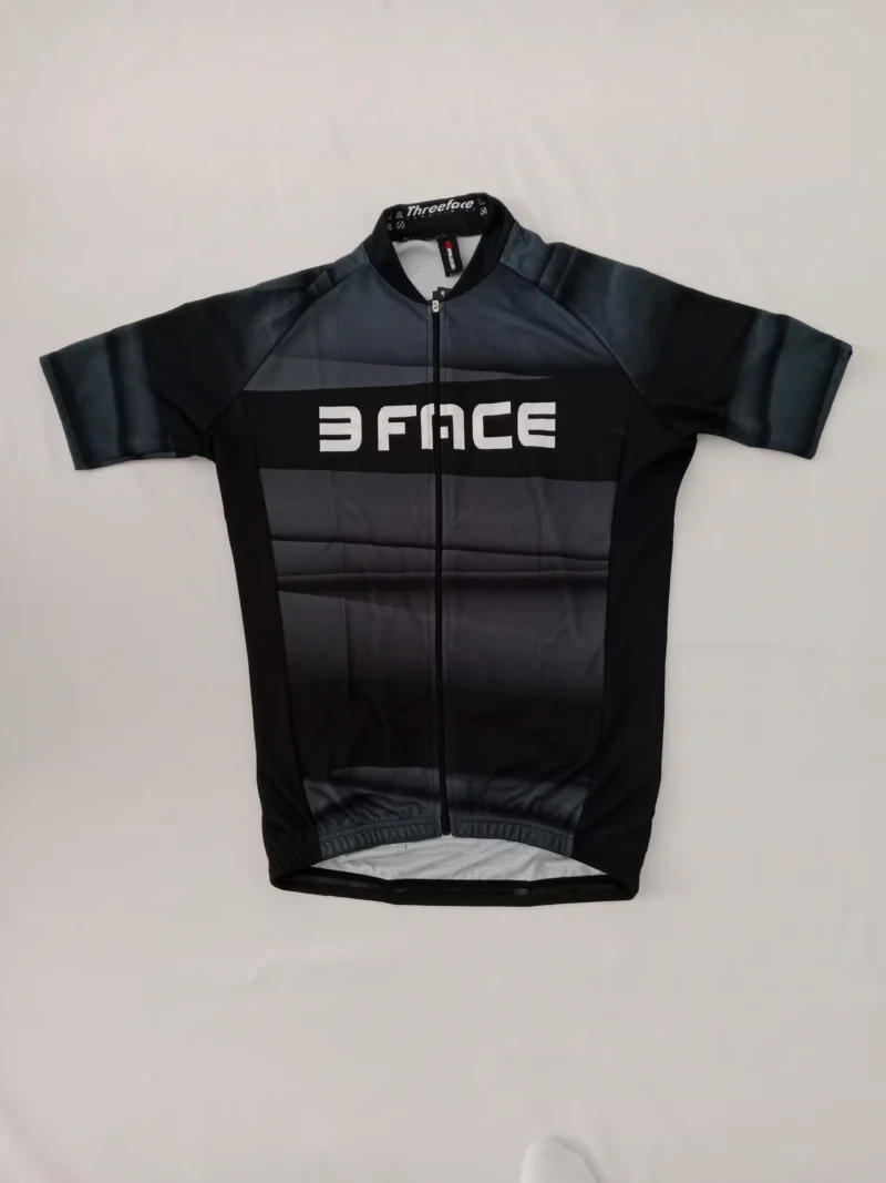 Schwarzes Spicy Radsporttrikot mit kurzem Arm, drei Rückentaschen und elastischem Bund, auf weißem Hintergrund fotografiert.